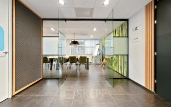 Modern office space in Almere Stad with glass doors, stylish furniture, and a conference setup. Ideal for office space rental at Jool Hulstraat 2-14.