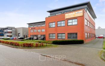 Exterior view of red-bricked office building on Jool Hulstraat 2-14, Almere Stad, featuring available office space rental with visible parking.