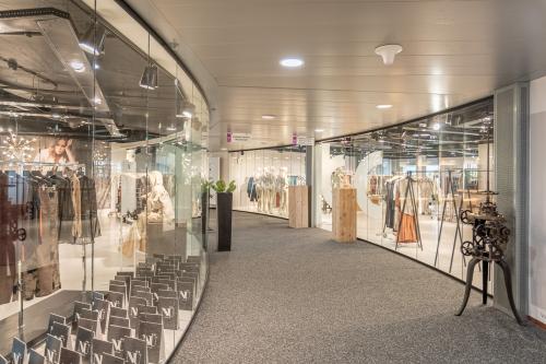 Curved glass entrance showcasing two modern boutiques with stylish clothing displays at Veluwezoom 5, Almere Veluwsekant. Ideal location for office space rental in a vibrant setting.