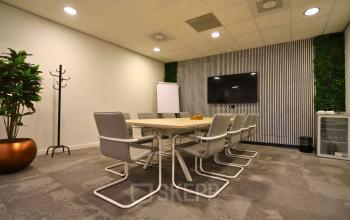 Furnished conference room at Leidse Schouw 2, Alphen aan den Rijn with a modern table, chairs, TV, and a small fridge for office space rental.