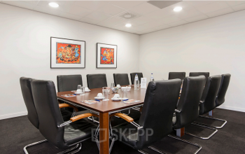 Conference room at Leidse Schouw 2, Alphen aan den Rijn, featuring a long table with black chairs, surrounded by art on the walls, ideal for office space rental.