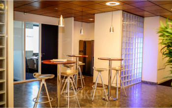 Modern office space at Leidse Schouw 2, Alphen aan den Rijn, featuring high-top tables and chairs in a cozy setting for rental opportunities.