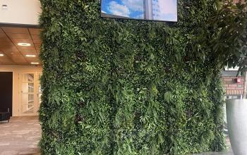 Bright lobby at Leidse Schouw 2, Alphen aan den Rijn with a lush green wall and TV screen, ideal for office space rental.