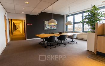 Bright office space for rent at Europalaan 16, Alphen aan den Rijn with modern furniture, including a large conference table, chairs, and a window view. Ideal for office space rental.