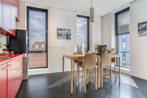 Bright office kitchen with red cabinets, tall table, and chairs at Flemingweg 8, Alphen aan den Rijn, featuring floor-to-ceiling windows.