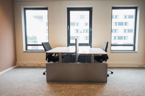 Interior view of a modern office space rental at Ruimtevaart 24, Amersfoort Calveen, featuring two desks and chairs positioned by large windows.