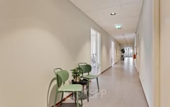 Interior hallway at Astronaut 28, Amersfoort Calveen, featuring minimalist design with two green chairs and a small table. Ideal for seeking office space rental in a modern business environment.