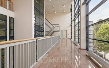 Bright, spacious hallway at Astronaut 28, Amersfoort Calveen, featuring modern glass walls and polished floors, perfect for easy navigation in this office space rental.