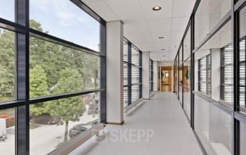 Modern office corridor at Astronaut 28, featuring large windows with a view of the greenery outside, suitable for office space rental in Amersfoort Calveen, Amersfoort.