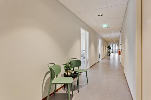 Interior hallway at Astronaut 28, Amersfoort Calveen, featuring minimalist design with two green chairs and a small table. Ideal for seeking office space rental in a modern business environment.