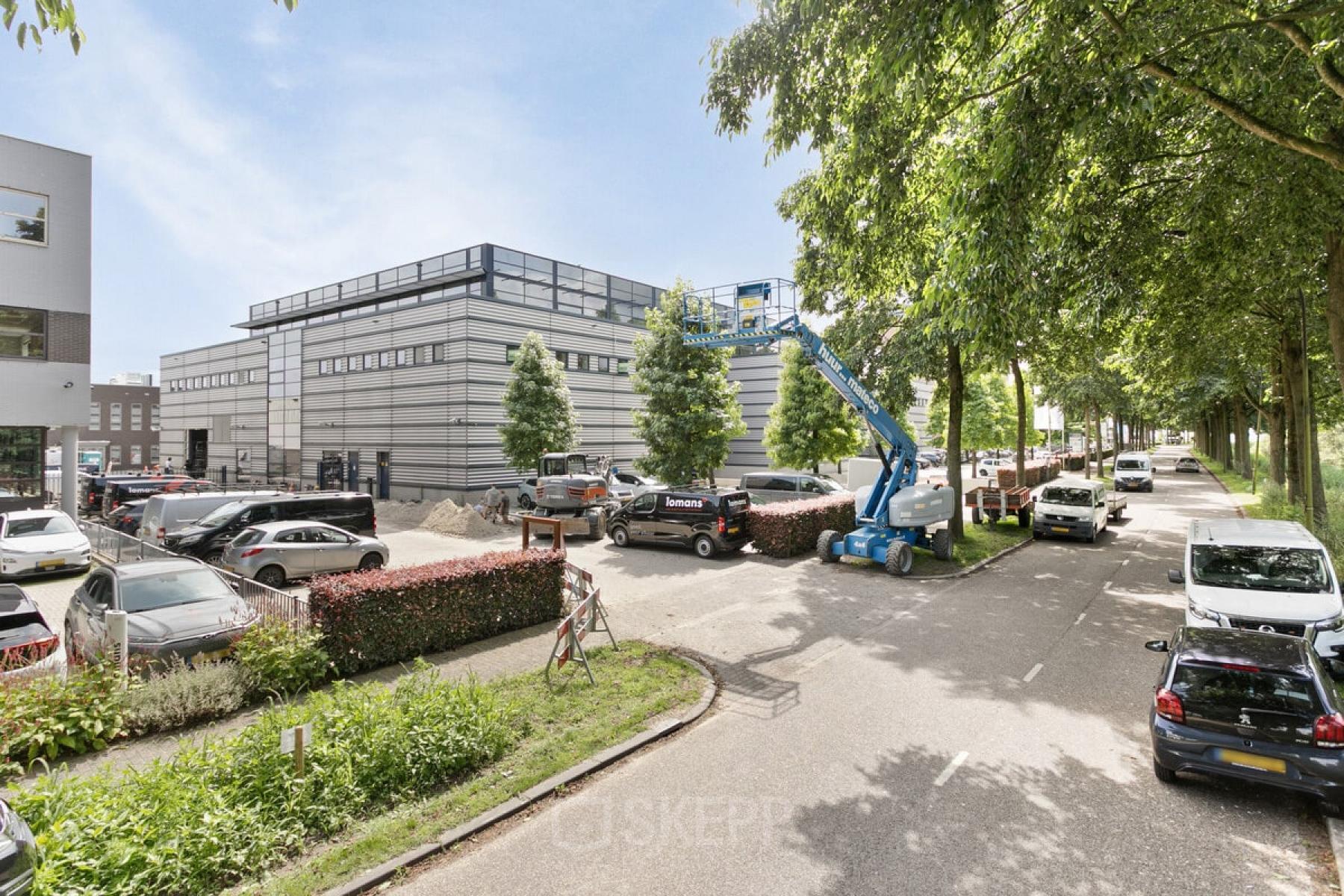 Exterior view of the office building at Astronaut 28, Amersfoort Calveen. The modern structure is surrounded by cars and trees, providing a professional setting for office space rental.
