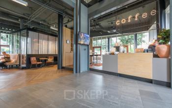 Modern office space rental at Maanlander 47 in Amersfoort Calveen featuring a welcoming area with seating and a coffee counter.