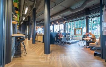 Modern office space at Maanlander 47, Amersfoort Calveen, featuring a furnished open floorplan with people engaging in discussions, ideal for rent office space needs.