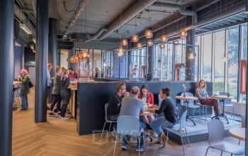 Modern interior at Maanlander 47, Amersfoort Calveen, with people engaging in conversations and enjoying the office lounge area. Ideal space for office space rental and networking.