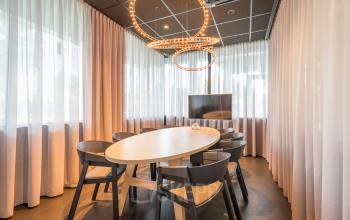 Bright office space rental at Maanlander 47, Amersfoort Calveen, featuring a well-lit conference room with stylish lighting and a flat-screen TV.