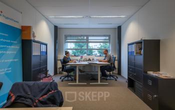 Two people working at desks in a furnished office space at Maanlander 47, Amersfoort Calveen, ideal for rent office space seekers.