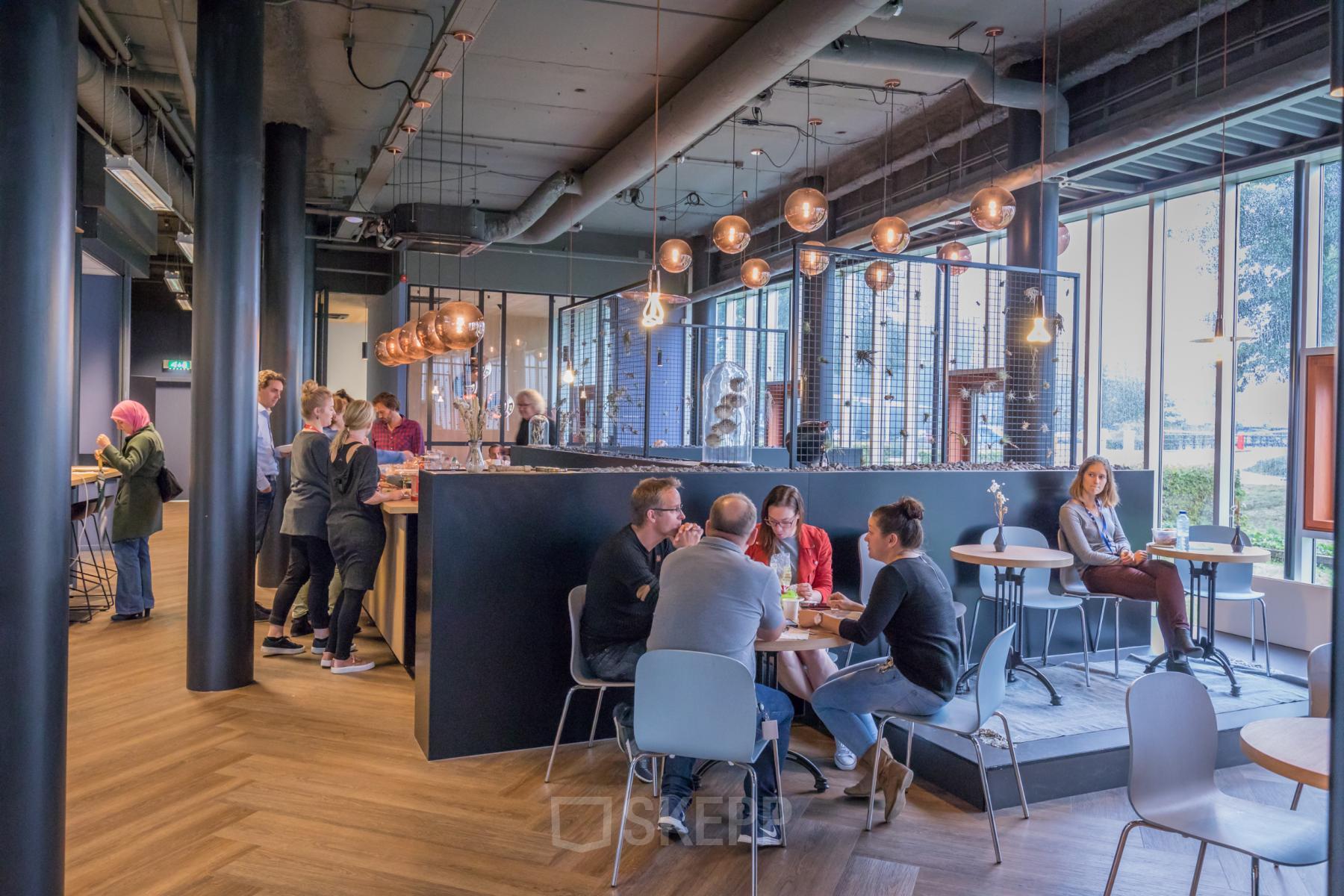 Modern interior at Maanlander 47, Amersfoort Calveen, with people engaging in conversations and enjoying the office lounge area. Ideal space for office space rental and networking.