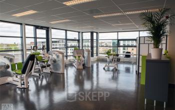 Modern office space rental at Piet Mondriaanplein 13-31, Amersfoort Centraal Station with a fitness area and large windows.