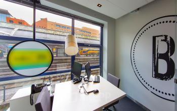Office space rental at Piet Mondriaanplein 13-31, featuring modern furnishings, ample natural light, and a view of Amersfoort Centraal Station.