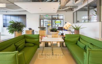 Modern Amersfoort office space rental with vibrant green sofas, communal working tables, and large windows at Piet Mondriaanplein 13-31.