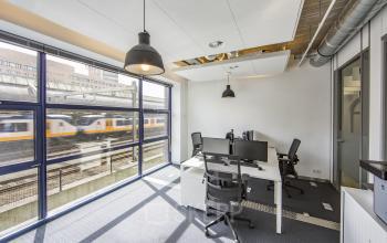 Bright office space rental at Piet Mondriaanplein 13-31, Amersfoort Centraal Station, with modern desks and rail view.