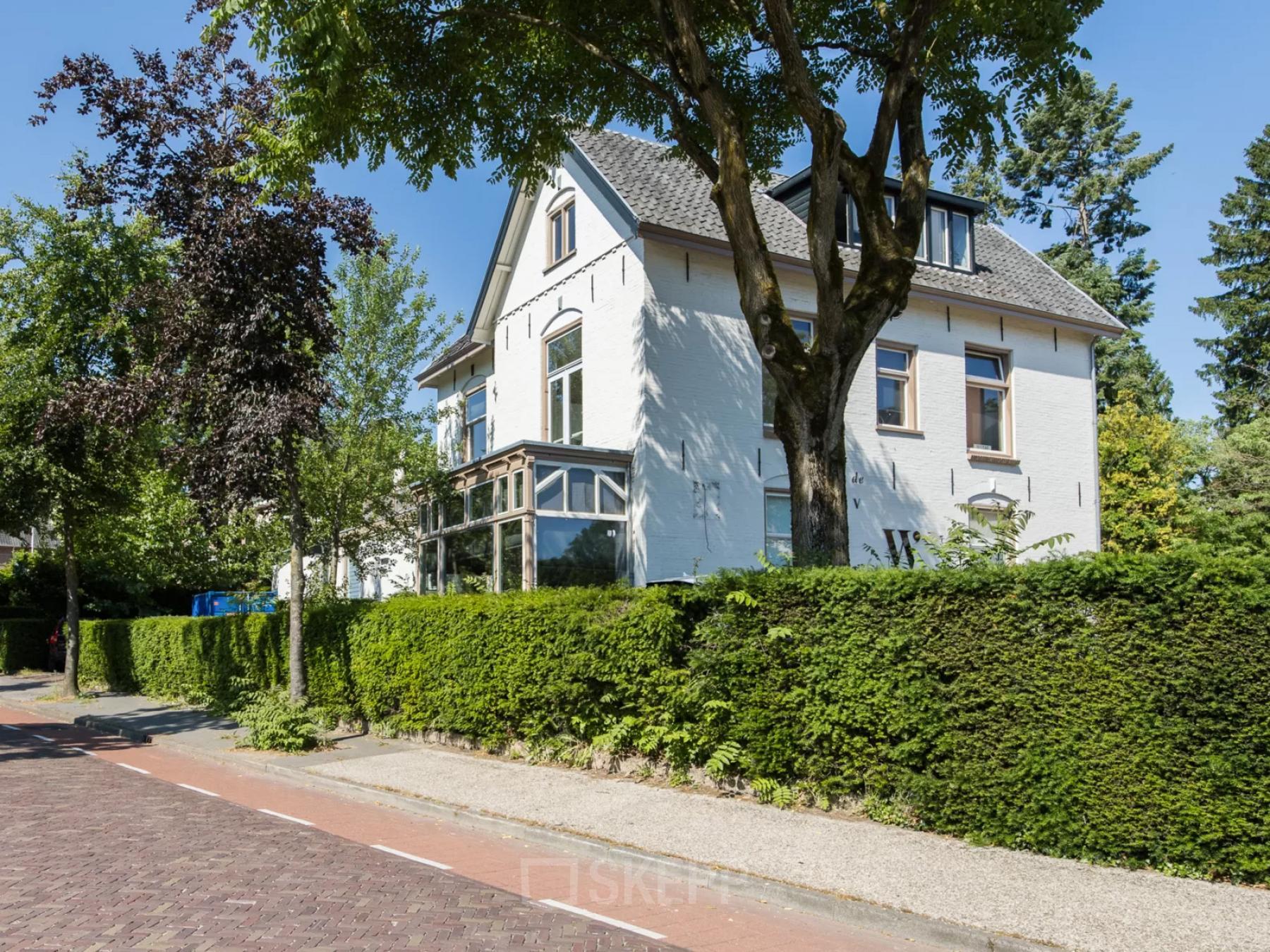 Exterior view of an office space for rent at Utrechtseweg 129, surrounded by lush greenery and trees in Amersfoort Centraal Station area.