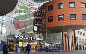 Exterior view of Amersfoort Centraal Station with modern design elements and people walking by.