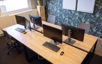 Comfortable office space rental at Amersfoort Centraal Station with wooden desks, computer monitors, and chairs for collaborative work.