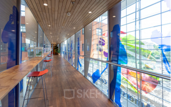 Bright corridor with high windows and colorful artwork at Amersfoort Centraal Station, ideal for break time in your rented office space.