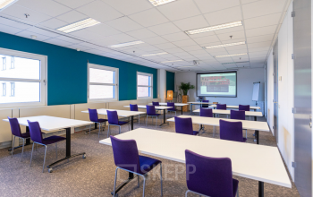 Bright office space with tables and purple chairs ideal for office space rental at Stationsplein 49, Amersfoort Centraal Station.