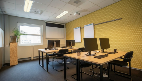 Modern office space with desks and computers at Stationsplein 49, Amersfoort Centraal Station, available for office space rental. The room features a projector and natural light.