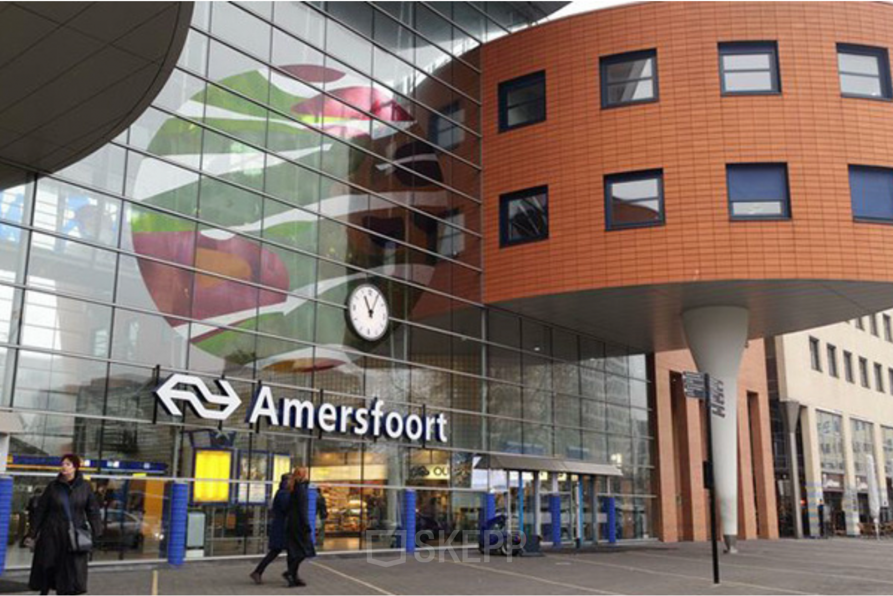 Exterior view of Amersfoort Centraal Station with modern design elements and people walking by.