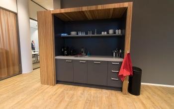 Modern pantry area in the office building at Smallepad 32, Amersfoort Centraal Station, with wooden flooring, a kitchenette, and various kitchen essentials.