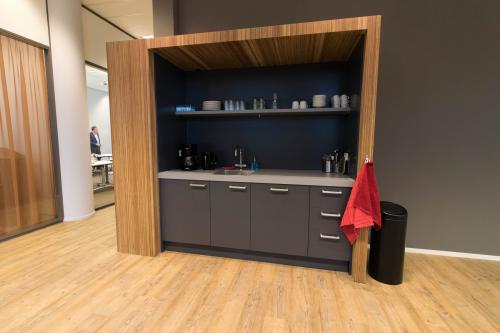 Modern pantry area in the office building at Smallepad 32, Amersfoort Centraal Station, with wooden flooring, a kitchenette, and various kitchen essentials.