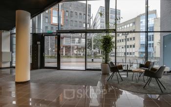 Modern office entrance at Van Asch van Wijckstraat 2-4 in Amersfoort Centrum featuring sleek glass doors and contemporary seating, ideal for businesses seeking office space rental.