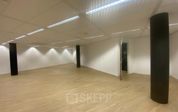 Unfurnished interior of an office to rent at Van Asch van Wijckstraat 2-4 in Amersfoort Centrum, featuring a spacious, open floorplan with wooden floors and ceiling lights.