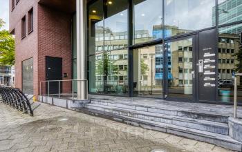 The modern exterior of the office building at Van Asch van Wijckstraat 2-4, Amersfoort Centrum, features a sleek glass entrance, perfect for businesses looking for office space rental in a prime location.