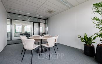 Modern office space for rent at Stadsring 201, Amersfoort Centrum, featuring a round table with chairs and stylish potted plants, perfect for meetings or collaborative work.