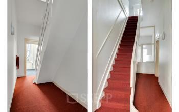 Interior view of Stadsring 248-250 in Amersfoort Centrum featuring a red-carpeted staircase and hallway, ideal for office space rental. Bright neutral walls flood the area with light, creating a welcoming entrance.