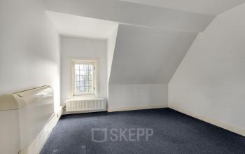 A compact, unfurnished office space at Stadsring 248-250 in Amersfoort Centrum, featuring a sloping ceiling and a windowed wall. Ideal for office space rental.