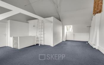 Spacious office interior at Stadsring 248-250 in Amersfoort Centrum, featuring high ceilings, a ladder, and carpeted flooring, ideal for open floor plan office space rental.