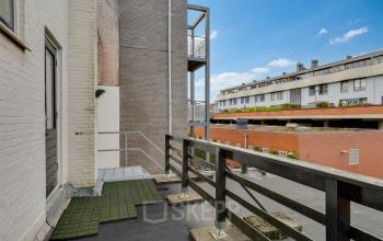 View of the exterior of an office space rental at Stadsring 248-250, Amersfoort Centrum. The photo shows a concrete and brick facade with a simple balcony area, surrounded by other buildings.