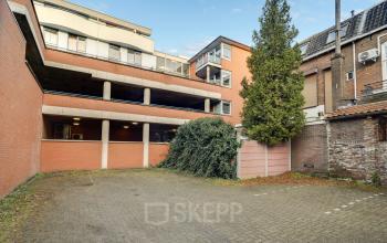 Exterior view of Stadsring 248-250 in Amersfoort Centrum, showcasing a brick building with a paved courtyard and surrounding greenery. Ideal space for office space rental.