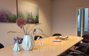 Office space rental in Amersfoort De Hoef featuring a meeting table adorned with modern decor under geometric paintings.