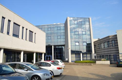 Exterior view of office space rental at Algolweg 9-11, featuring a modern facade with large windows and an adjacent parking area in Amersfoort De Hoef.
