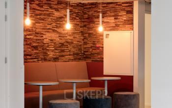 Modern office interior at Vanadiumweg 11, Amersfoort Isselt, featuring a cozy seating nook with stylish lighting and textured walls, ideal for meetings or breaks. Perfect office space rental option.