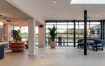 Modern office space rental at Vanadiumweg 11, Amersfoort Isselt. Features stylish seating areas with large windows providing abundant natural light, ideal for professional gatherings.