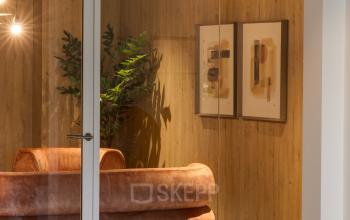 Stylish office interior featuring a plush sofa with wooden paneling and elegant artwork at Vanadiumweg 11 in Amersfoort Isselt, ideal for office space rental.