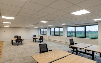 Bright office space rental at Vanadiumweg 11, Amersfoort Isselt featuring large windows with countryside views, modern lighting, and neatly arranged desks and chairs for a productive work environment.
