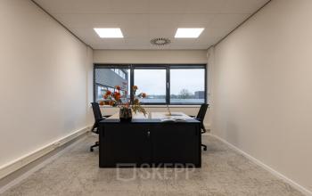 Bright office space at Vanadiumweg 11, Amersfoort Isselt, featuring a large window and minimalistic furnishings, suitable for office space rental.